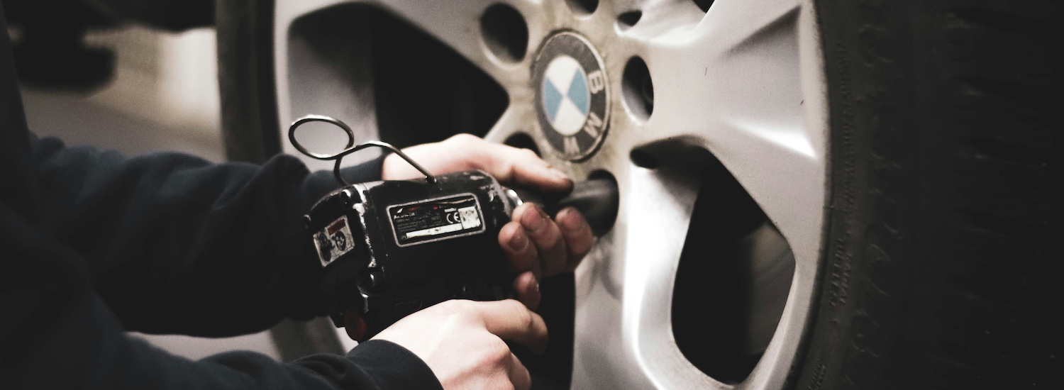 Car mechanic changing a BMW car tyre for fleet management